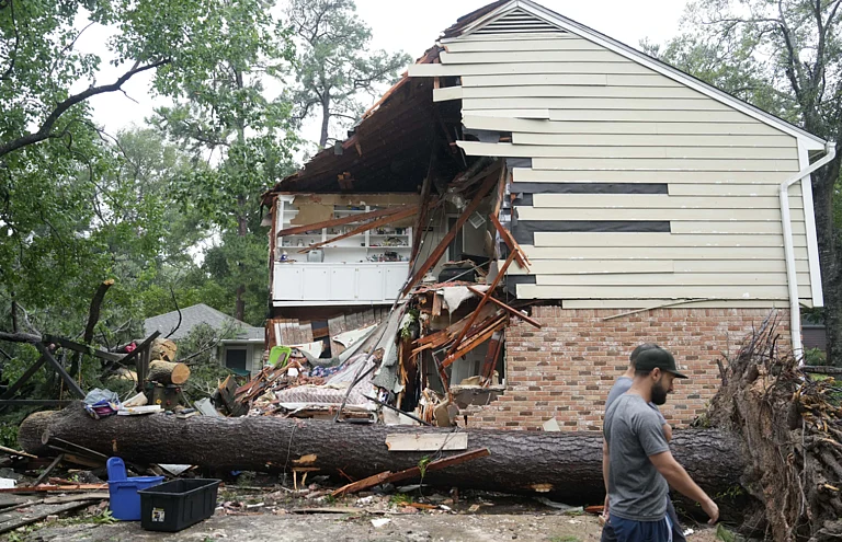 People gather outside a home where Maria Loredo was killed when a tree crashed through her roof. - AP